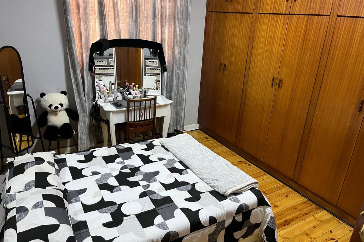 A bedroom featuring polished wooden flooring and extensive built-in wooden cabinetry providing ample storage space.