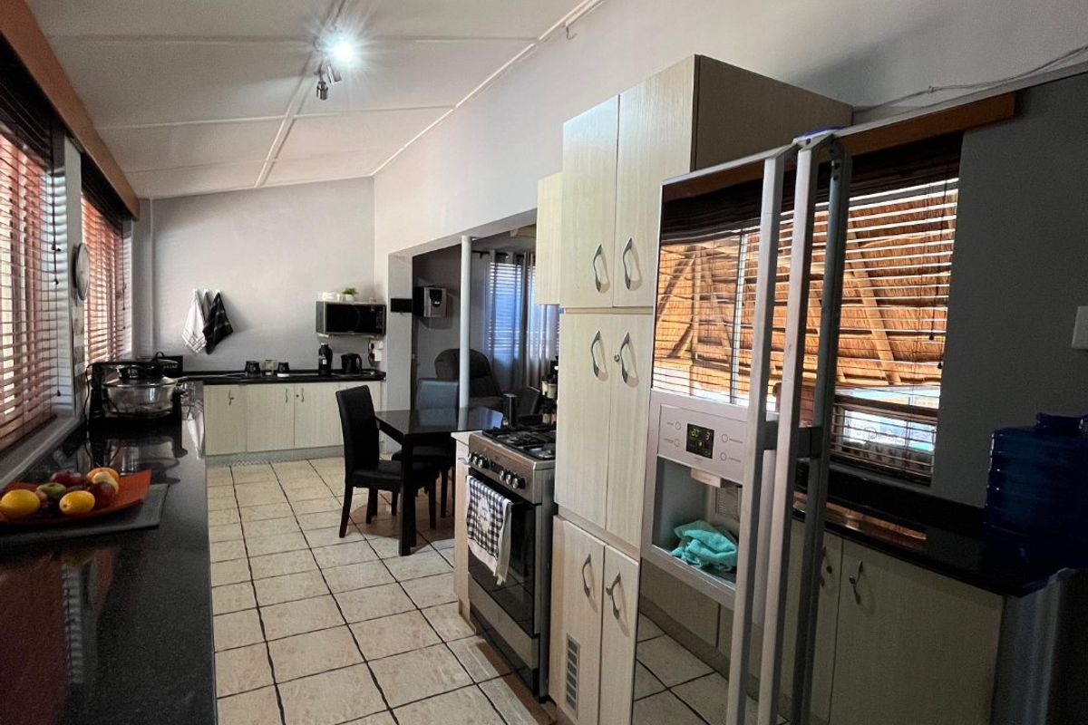 A functional kitchen featuring granite countertops, tiled flooring, and built-in cabinetry with integrated stainless steel appliances.