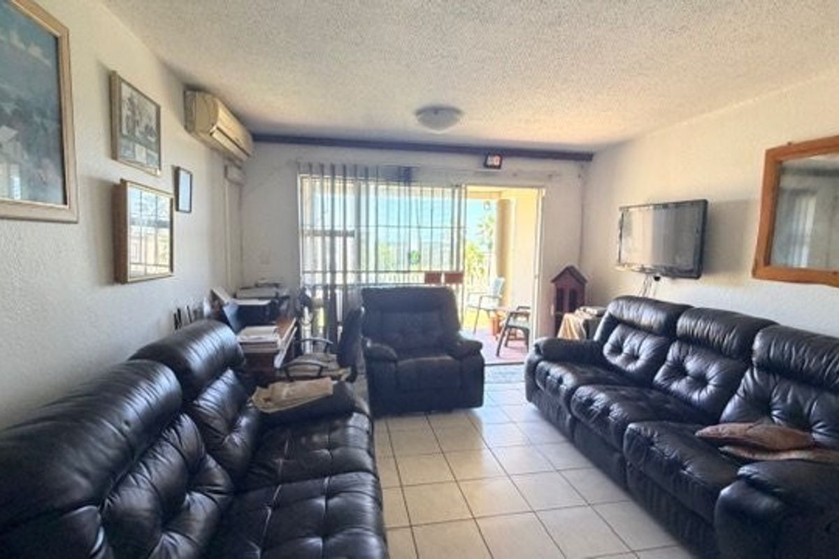 A living room featuring ceramic tile flooring, a split-system air conditioner, and a sliding glass door providing access to an outdoor balcony area.