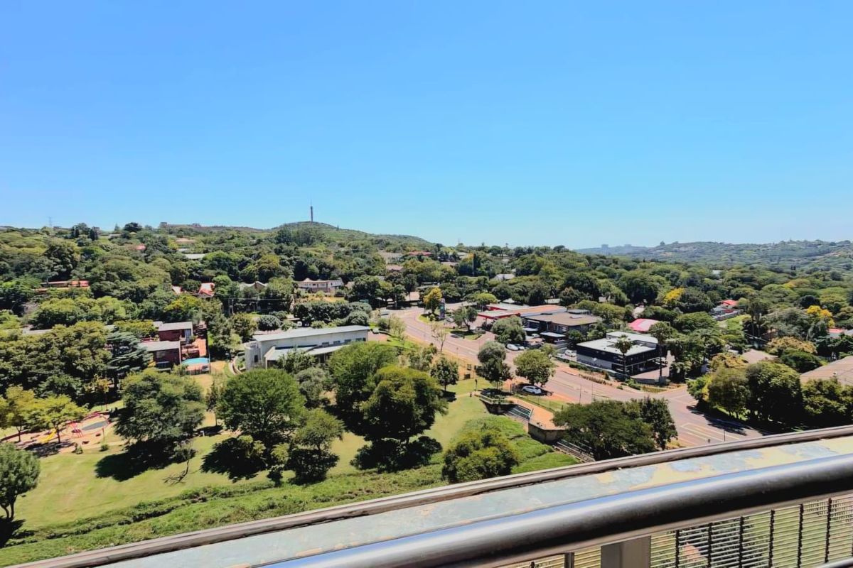 Elevated panoramic view overlooking a lush suburban landscape with mature trees and local commercial infrastructure.