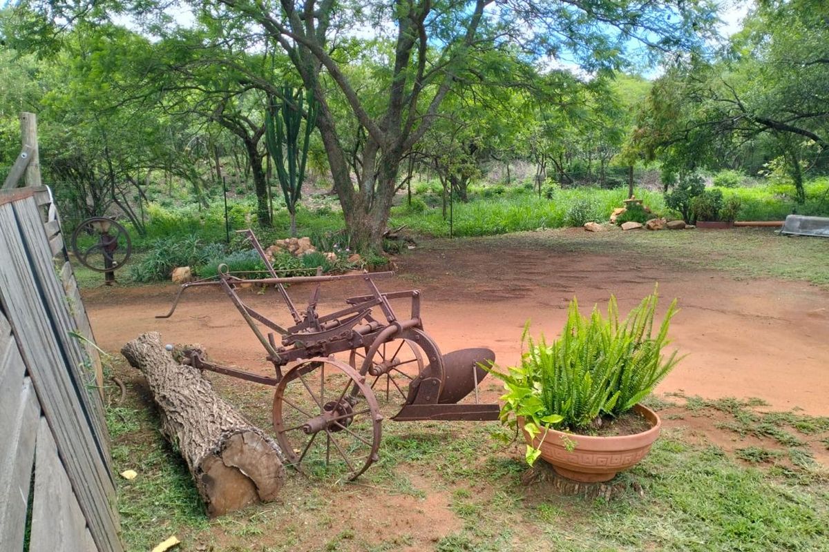 A spacious, natural garden area featuring mature trees, a rustic wooden fence, and open grounds on a farm property.