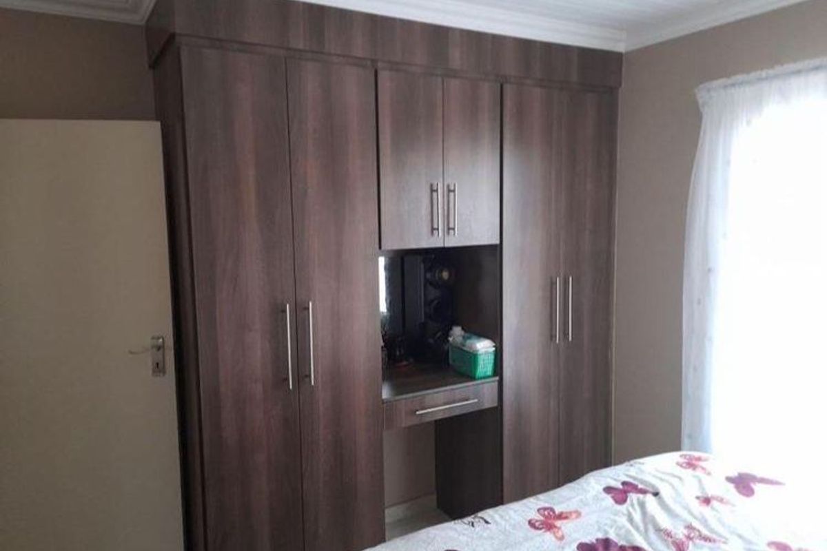 A bedroom featuring dark wood built-in cupboards with an integrated vanity unit and coved ceiling detailing.