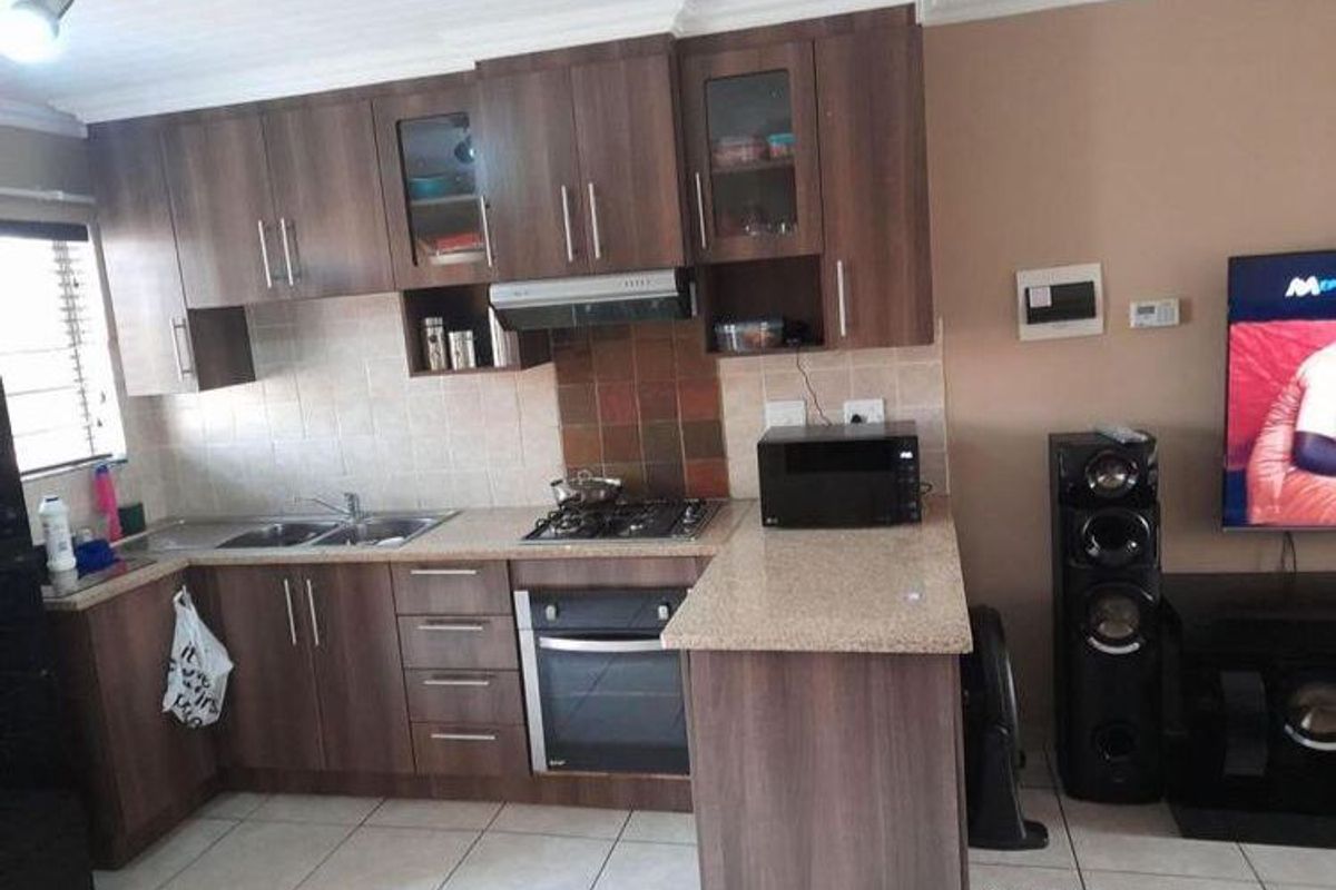Open plan kitchen featuring laminate cabinetry, stone countertops, built-in oven, gas hob, and tiled flooring, seamlessly integrated with the living area.