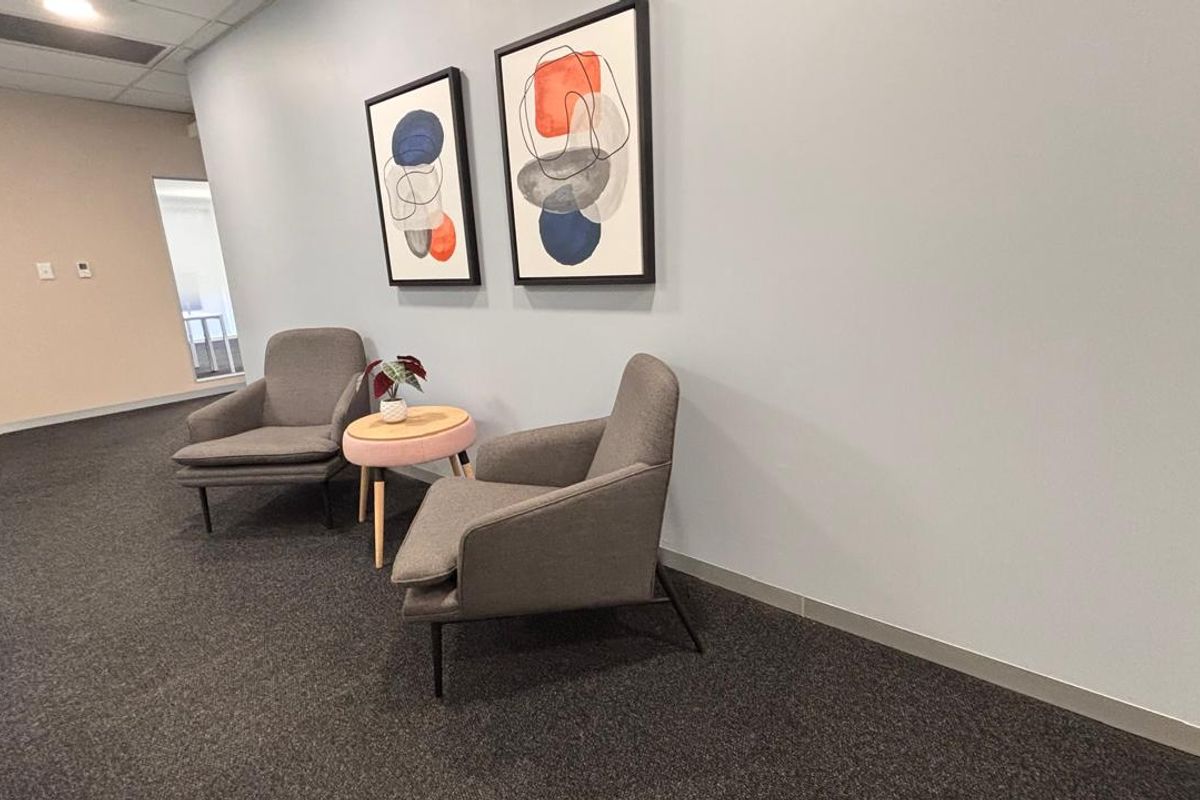 A clean, well-maintained commercial hallway featuring neutral wall tones, recessed ceiling lighting, and durable carpet flooring.