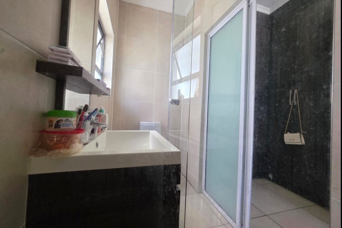 Modern bathroom featuring a vanity cabinet, basin, and a separate shower enclosure with a frosted glass door and tiled finishes.