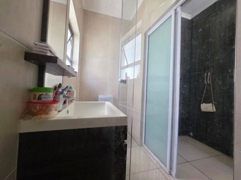 Modern bathroom featuring a vanity cabinet, basin, and a separate shower enclosure with a frosted glass door and tiled finishes.