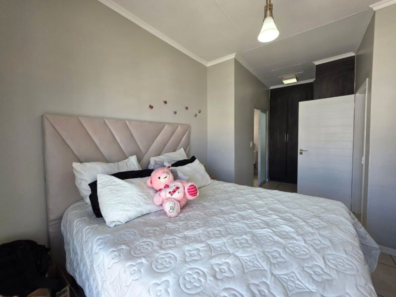A well-maintained bedroom featuring built-in cupboards, neutral wall finishes, and a modern pendant light fixture.