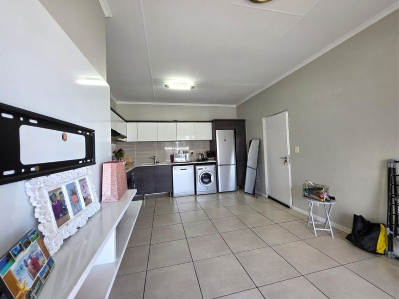 Open-plan living area featuring a functional kitchen with built-in cabinetry, tiled flooring, and a neutral color palette throughout the space.
