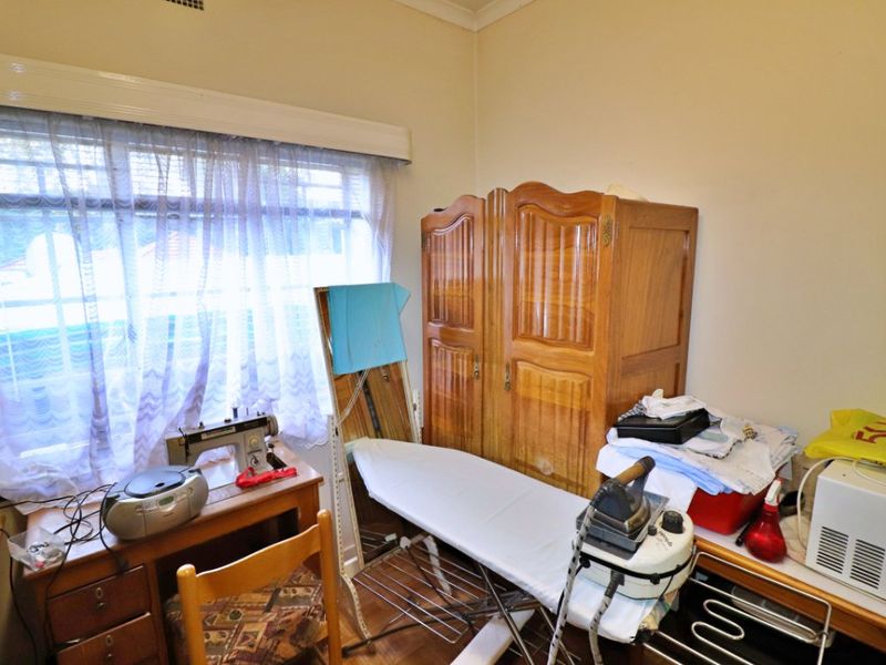 A functional bedroom space featuring timber flooring and a large window, offering a versatile area for various uses.
