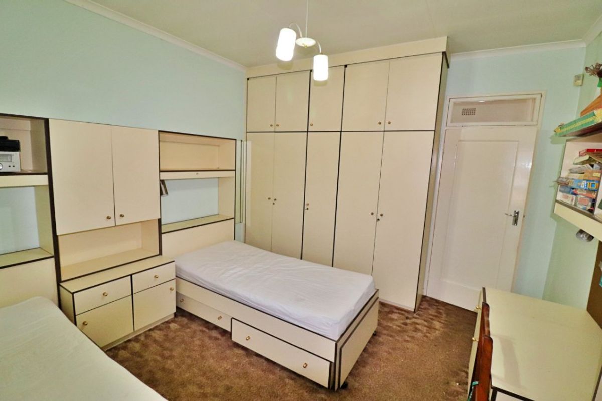 A bedroom featuring extensive built-in cabinetry, integrated shelving, and a built-in headboard, providing ample storage space within a functional layout.