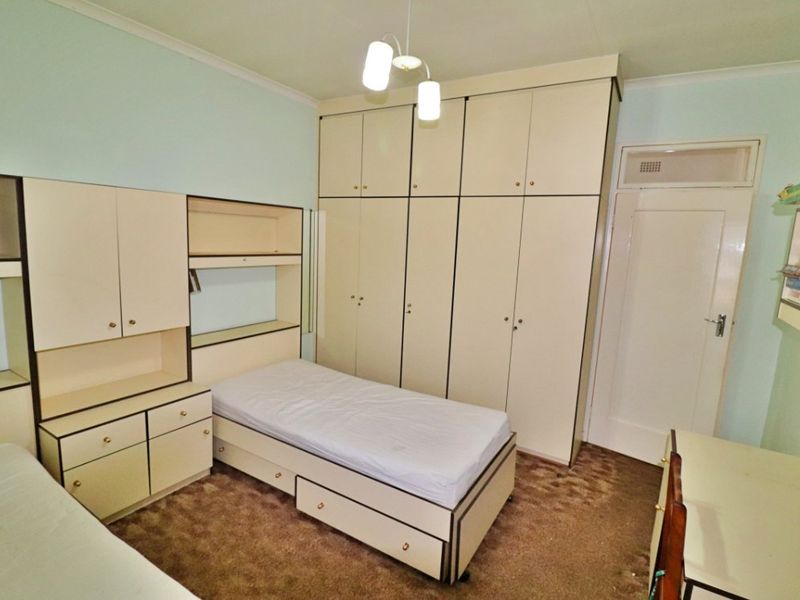 A bedroom featuring extensive built-in cabinetry, integrated shelving, and a built-in headboard, providing ample storage space within a functional layout.
