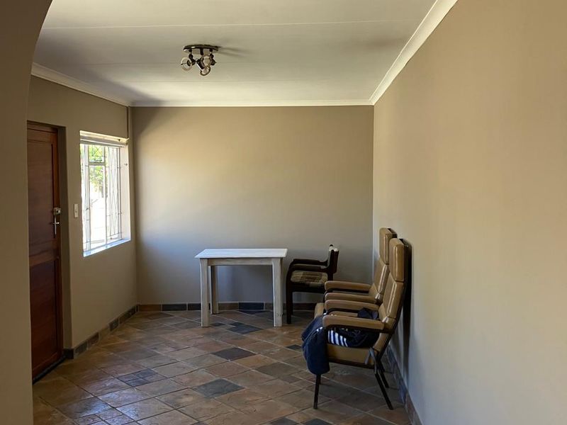 A living area featuring tiled flooring, a distinctive arched entrance, and a window with security bars, offering a neutral canvas for interior design.