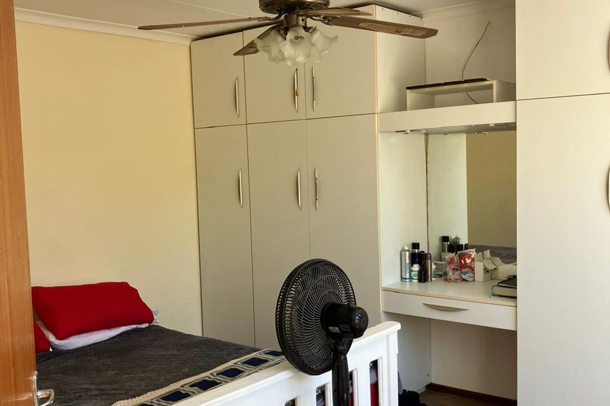 Bedroom featuring built-in cupboards, a vanity unit, ceiling fan, and tiled flooring.