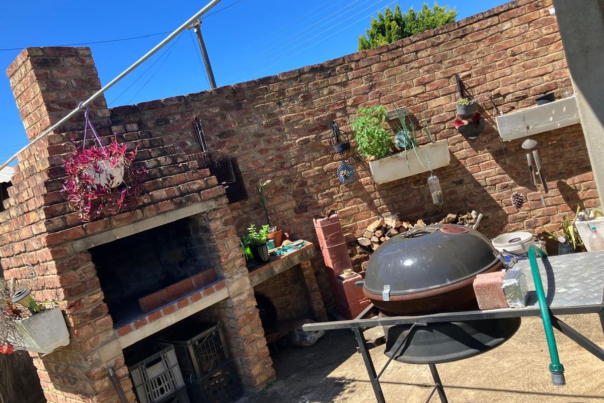 Outdoor entertainment area featuring a built-in brick braai and a private brick boundary wall, providing a functional space for outdoor cooking and relaxation.