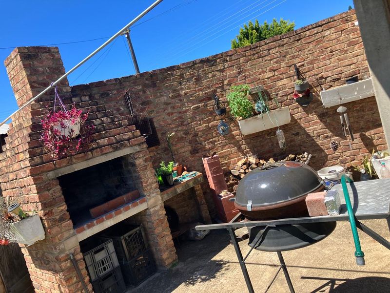 Outdoor entertainment area featuring a built-in brick braai and a private brick boundary wall, providing a functional space for outdoor cooking and relaxation.