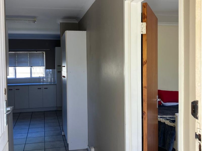 A functional hallway connecting the living area to the kitchen and bedroom, featuring tiled flooring and a built-in storage cupboard.