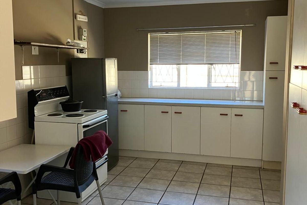 A functional kitchen featuring tiled flooring, built-in cabinetry, a tiled backsplash, and a freestanding stove, offering potential for modern updates.