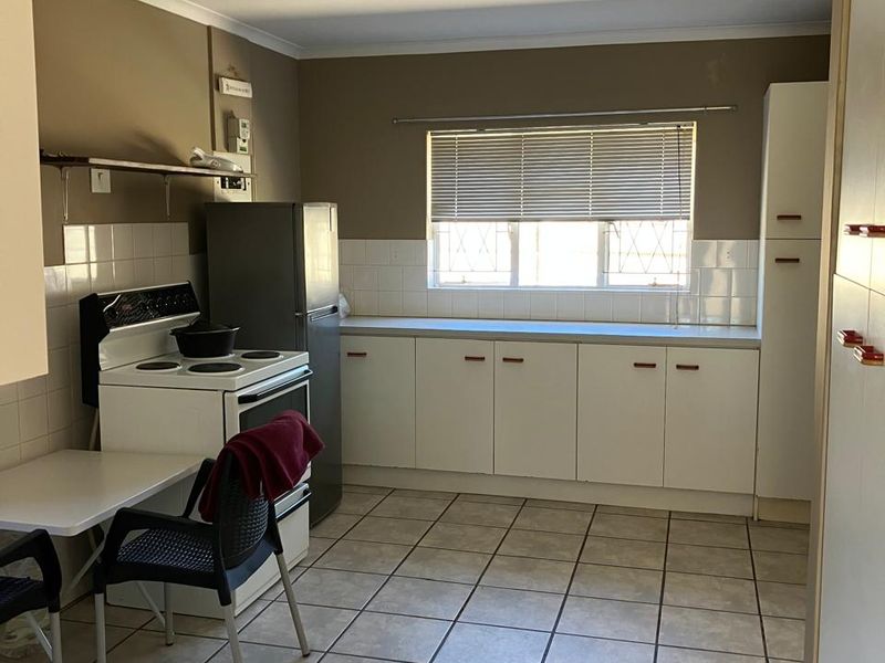 A functional kitchen featuring tiled flooring, built-in cabinetry, a tiled backsplash, and a freestanding stove, offering potential for modern updates.