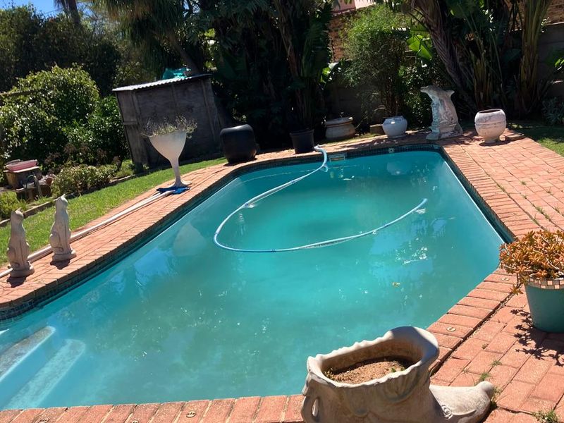Outdoor swimming pool area featuring a paved brick surround and established garden landscaping.