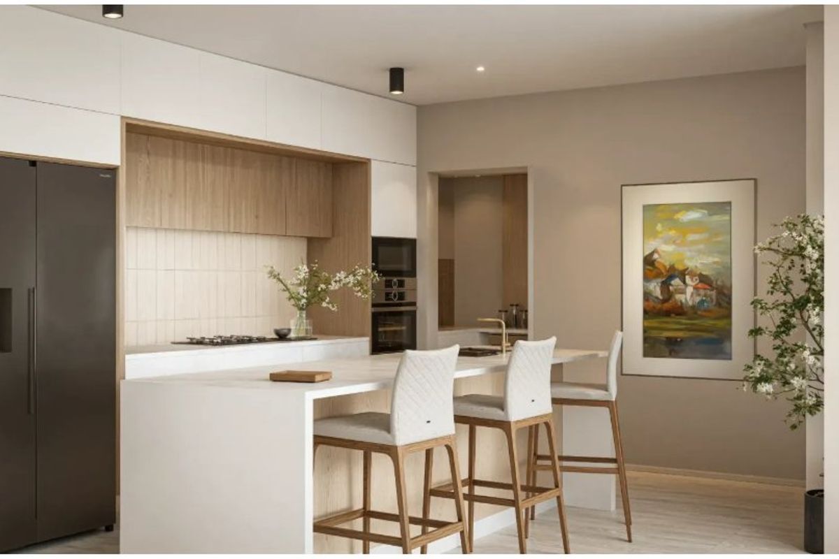 Modern kitchen featuring sleek white cabinetry, wood-toned accents, a stone island bench with breakfast seating, and integrated high-end appliances.