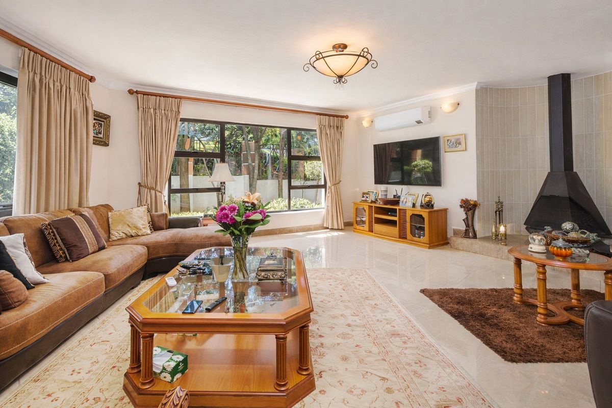 Spacious living room featuring tiled floors, a modern freestanding fireplace, and large windows providing natural light and garden views.