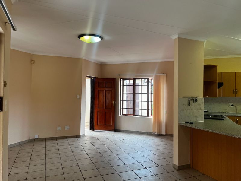 Spacious open-plan living area featuring tiled floors, a functional kitchen with granite countertops, and direct access to the exterior through a timber door.