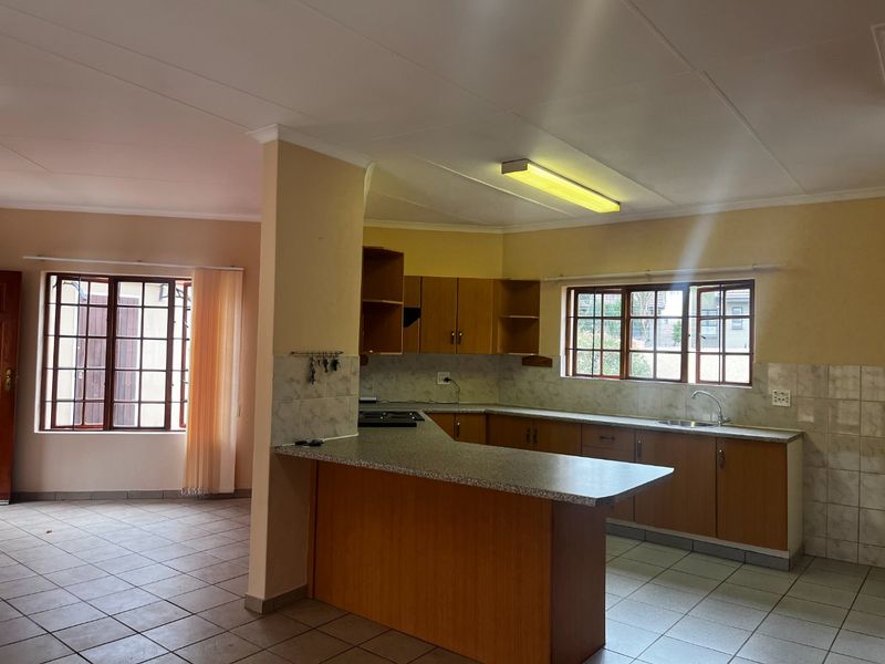 Open plan kitchen and living area featuring wooden cabinetry, laminate countertops, and tiled flooring throughout.