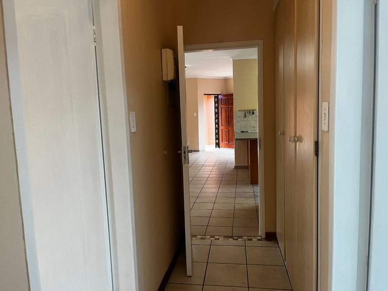 A functional hallway featuring built-in storage cupboards and ceramic floor tiles, providing access to the main living area and kitchen.