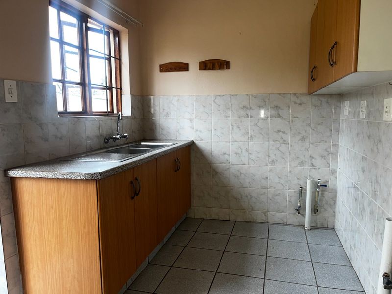 A functional kitchen area featuring laminate cabinetry, a stainless steel sink, tiled backsplash, and dedicated plumbing connections for a washing machine or dishwasher.