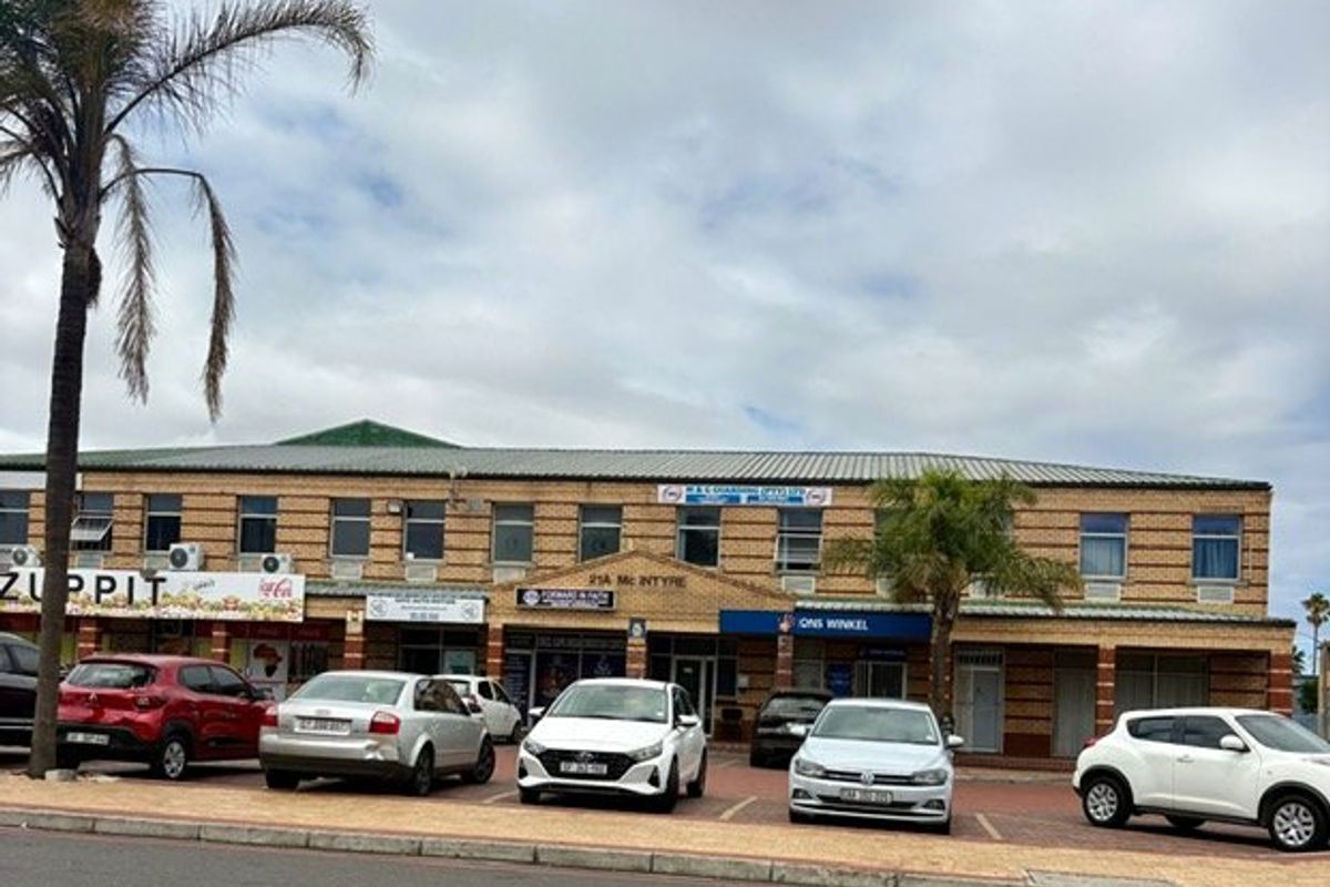 Front elevation of a commercial strip mall featuring brick facade, multiple storefronts, and dedicated paved parking area.
