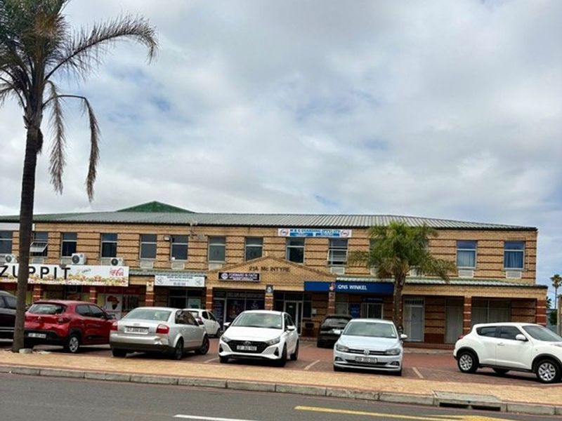 Front elevation of a commercial strip mall featuring brick facade, multiple storefronts, and dedicated paved parking area.