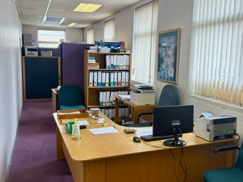 A functional commercial office space featuring suspended ceilings, recessed lighting, vertical blinds, and carpeted flooring.