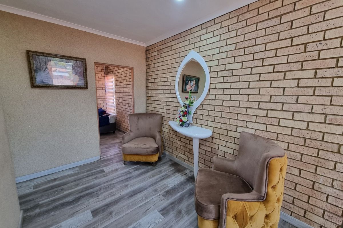 A living area featuring a textured brick feature wall, modern laminate flooring, and recessed ceiling lighting, providing a warm and inviting atmosphere.