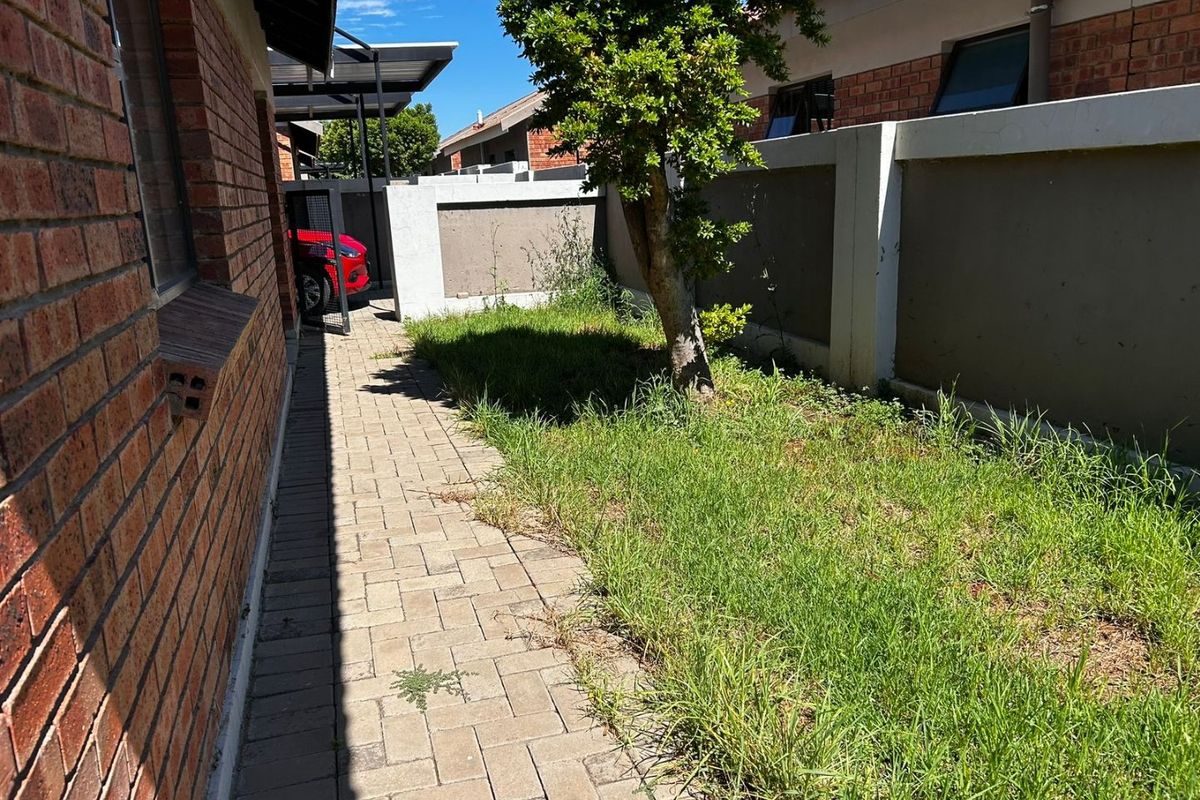 A side garden area featuring brick paving and a boundary wall, requiring landscaping maintenance to improve the outdoor space's appearance.