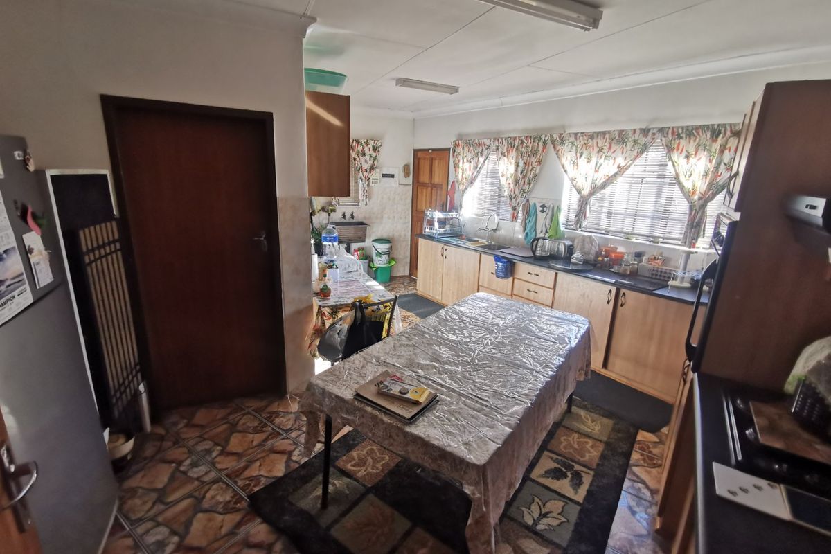 A functional kitchen featuring built-in wooden cabinetry, laminate countertops, a double basin sink, and tiled flooring, offering potential for modern updates.