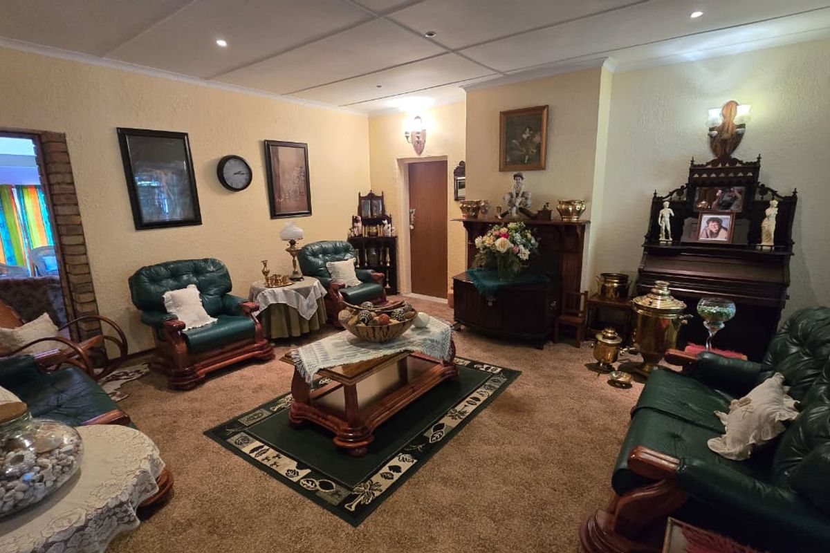A traditional living room featuring textured walls, carpeted flooring, and recessed lighting, with a brick archway leading to an adjacent space.