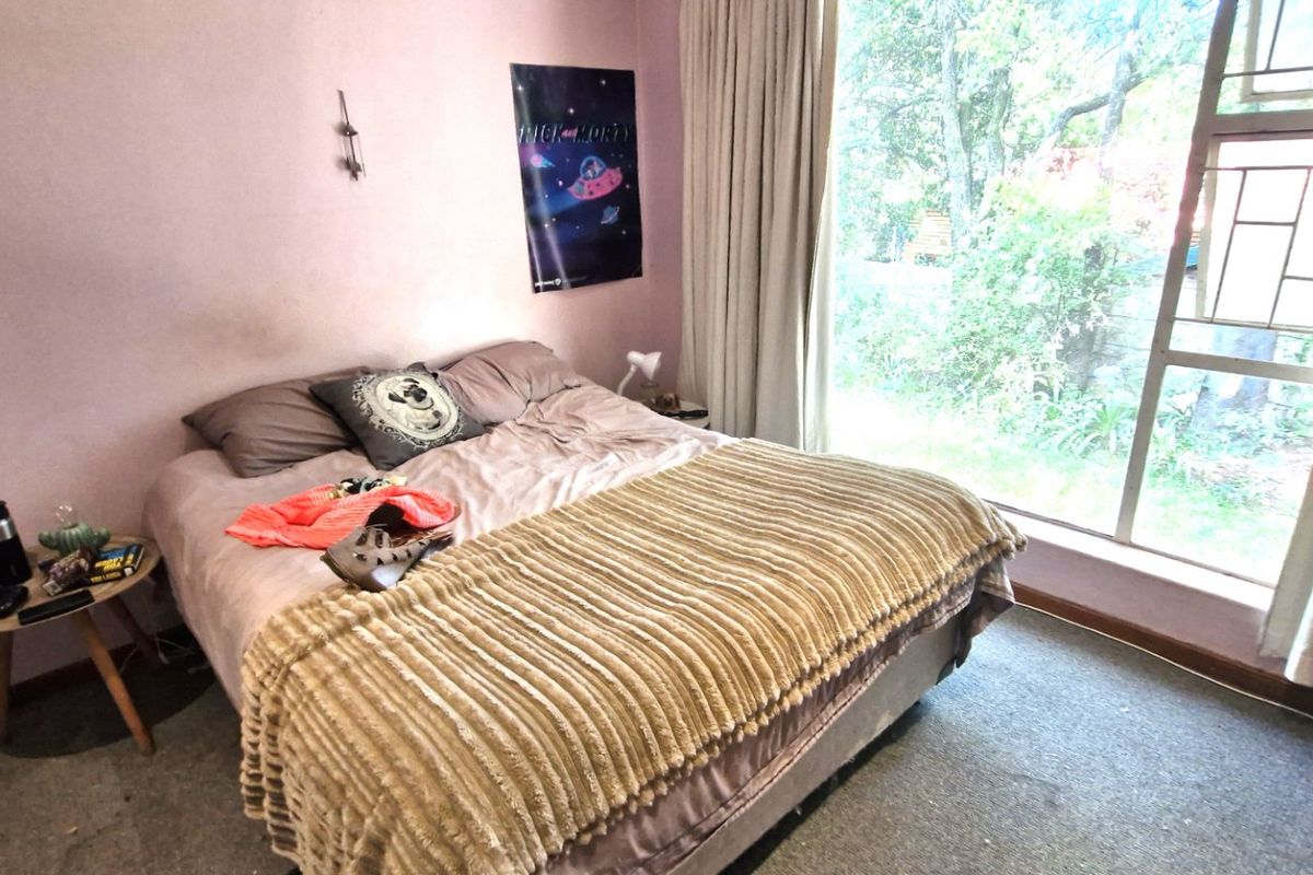 A bedroom featuring carpet flooring and a large window providing natural light and garden views.