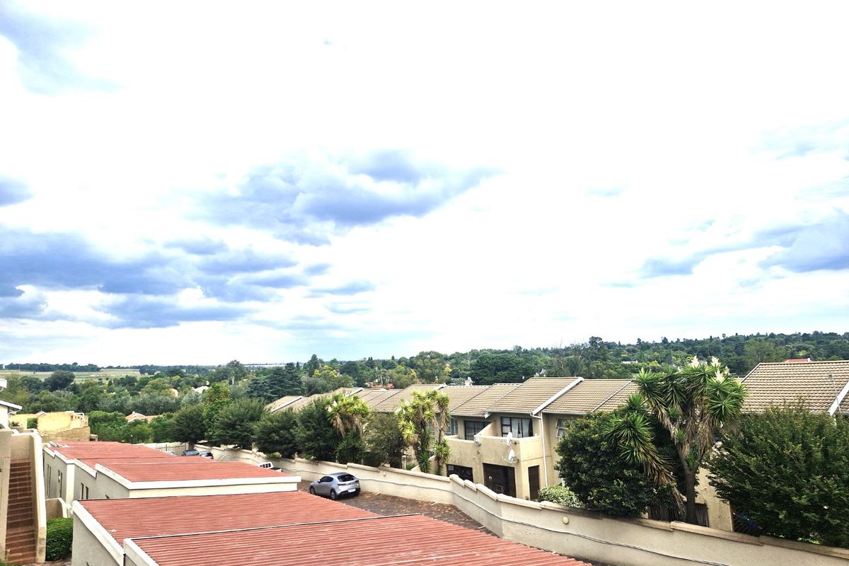 An elevated aerial view of the townhouse complex, showcasing the roof structures, surrounding boundary walls, and the established neighborhood landscape.