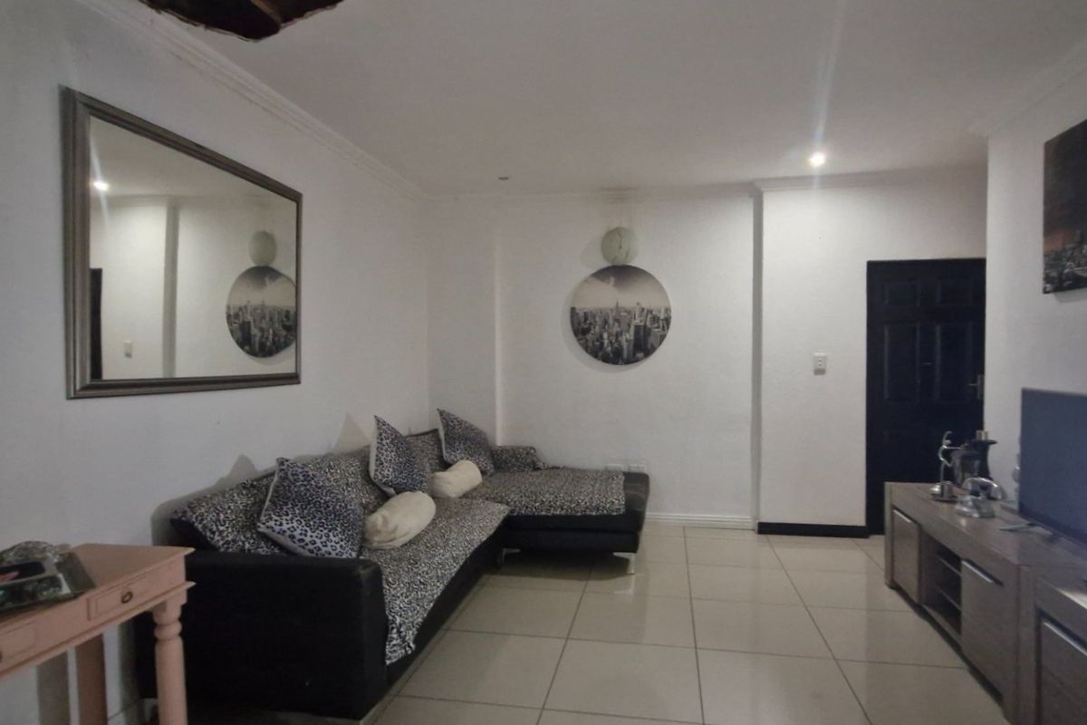 A living room featuring tiled flooring and recessed lighting, showing visible ceiling damage requiring repair.