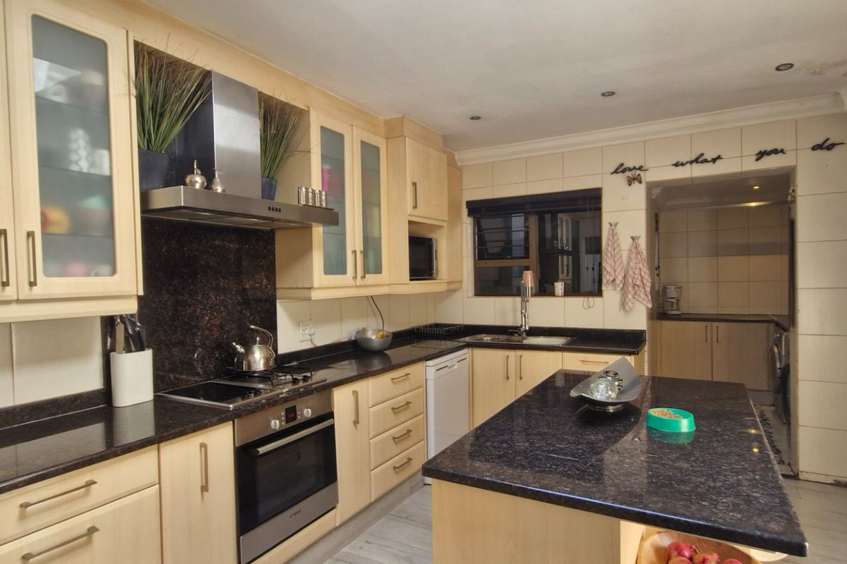 A functional kitchen featuring granite countertops, a central island, and built-in appliances, though the ceiling shows signs of water damage requiring repair.