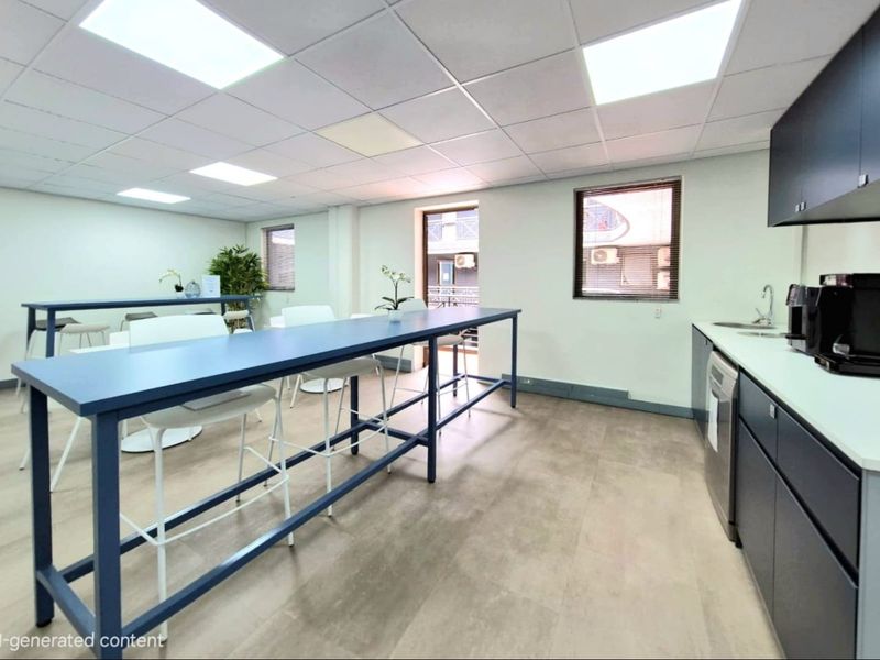 Modern commercial kitchenette and break area featuring sleek dark cabinetry, integrated sink, and durable flooring with recessed ceiling lighting.