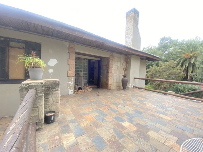 Spacious covered patio featuring natural stone paving, timber railings, and direct access to the home through a glass block entrance.
