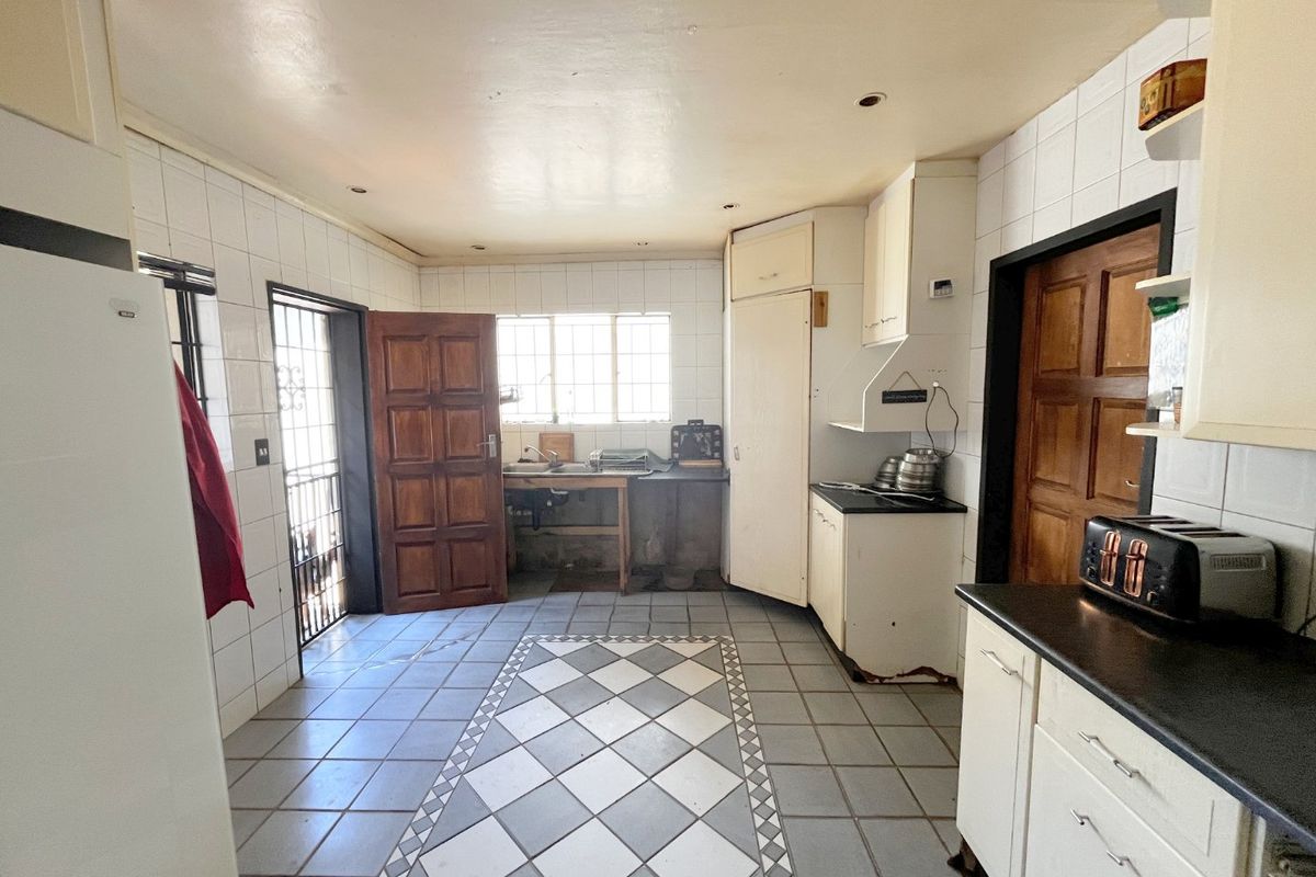A dated kitchen featuring tiled flooring, basic cabinetry, and a functional layout with direct access to an exterior door.