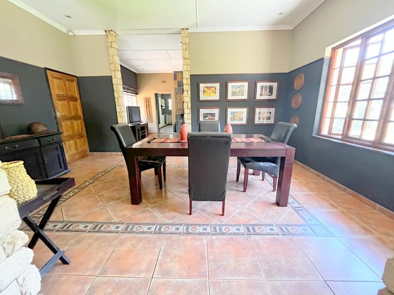 Spacious dining room featuring decorative tiled flooring, stone-clad pillar accents, and large windows allowing for natural light.