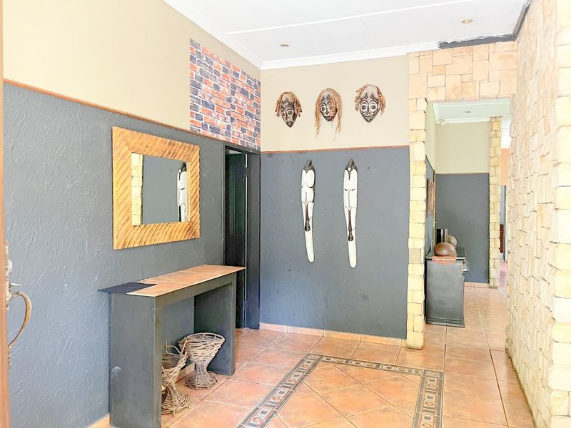 Entrance hall featuring tiled flooring with decorative inlay, stone-clad pillar accents, and a transition into the interior hallway.