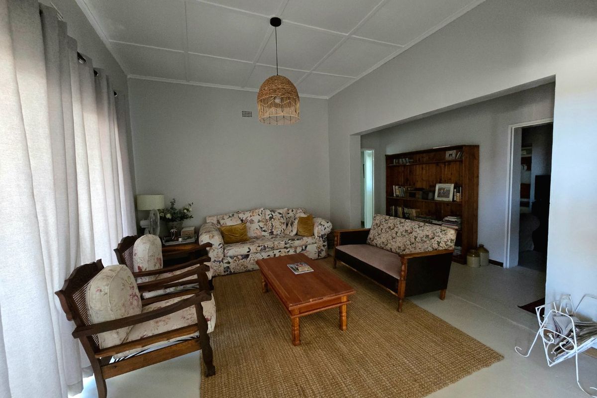 A spacious living room featuring tiled flooring, a built-in wooden shelving unit, and a classic ceiling design, offering a comfortable and functional living space.