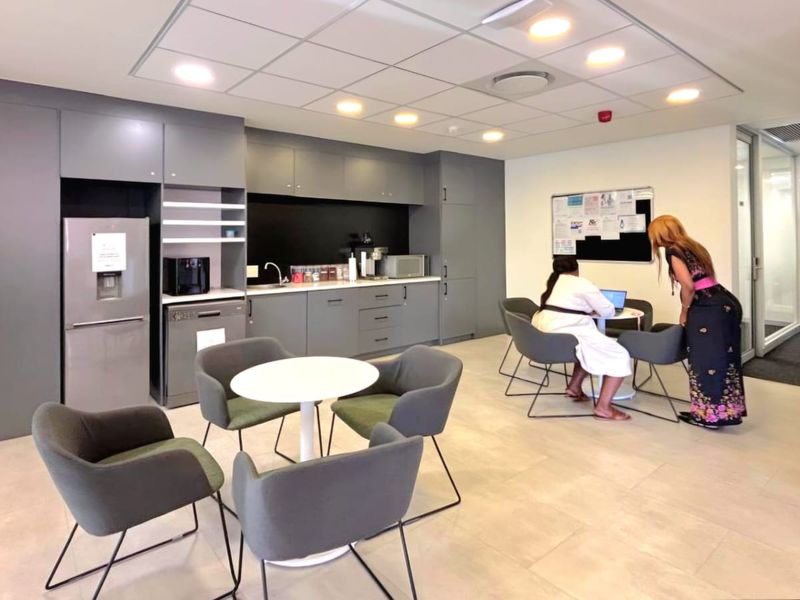 Modern commercial kitchenette featuring sleek grey cabinetry, integrated sink, and recessed ceiling lighting, providing a functional break area within the office space.