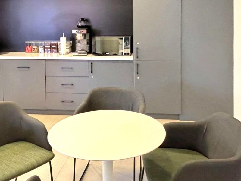 A compact commercial kitchenette featuring modern grey cabinetry, a clean countertop, and built-in microwave, suitable for office breakroom use.