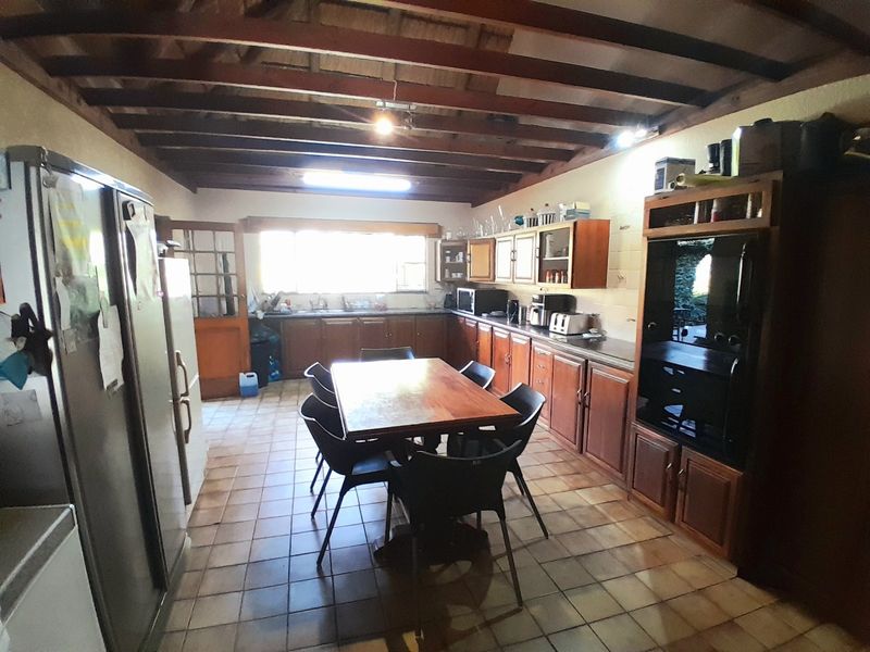 Spacious kitchen featuring exposed timber ceiling beams, tiled flooring, and extensive wooden cabinetry with integrated oven and ample counter space.