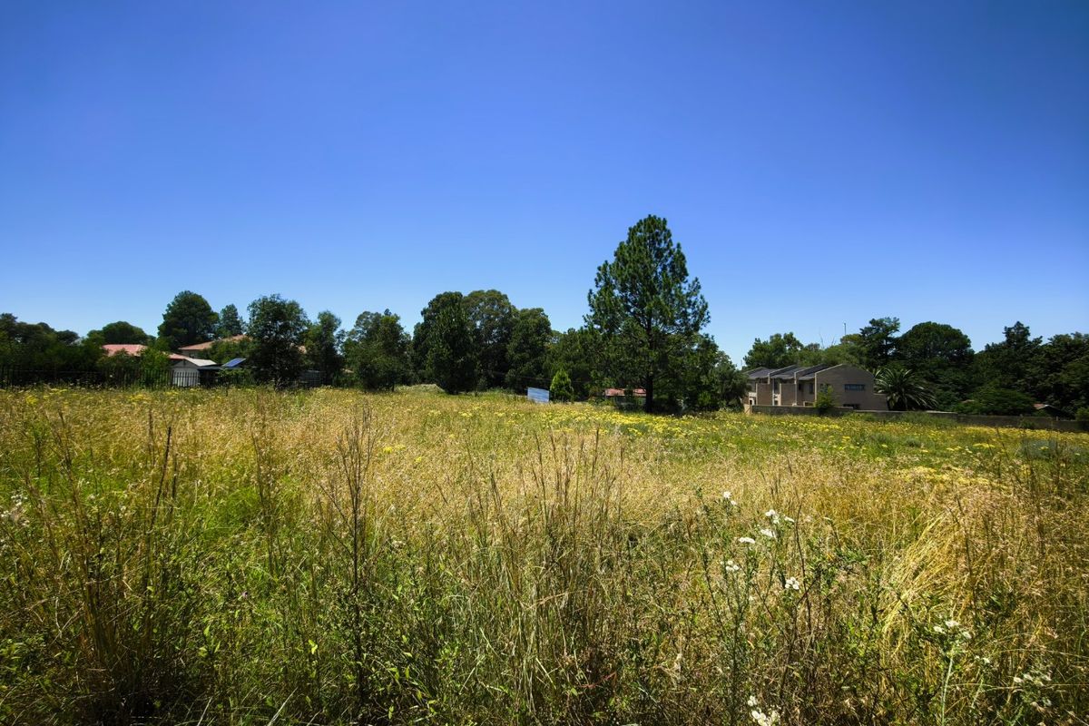 A wide, open plot of land featuring natural grass and mature trees, offering a blank canvas for potential development or landscaping.
